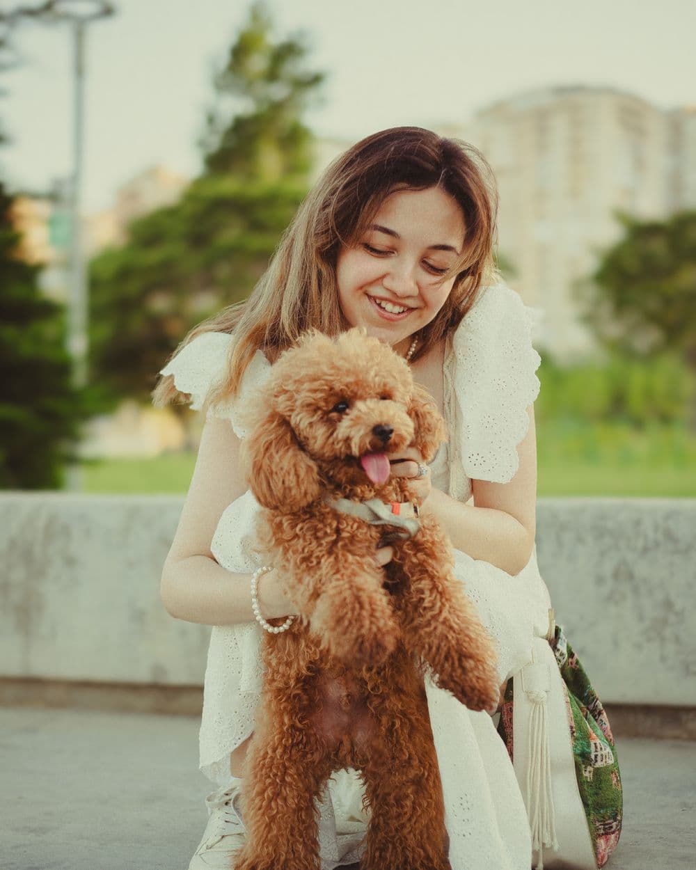 A woman smiling as she carries her poodle